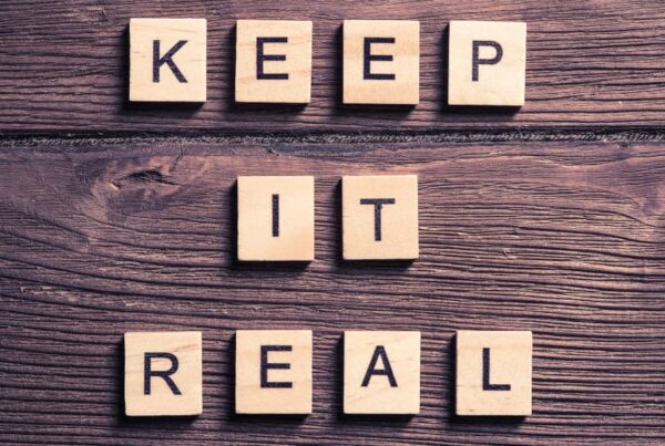 The phrase “Keep it real” on wooden tiles on a wooden table.